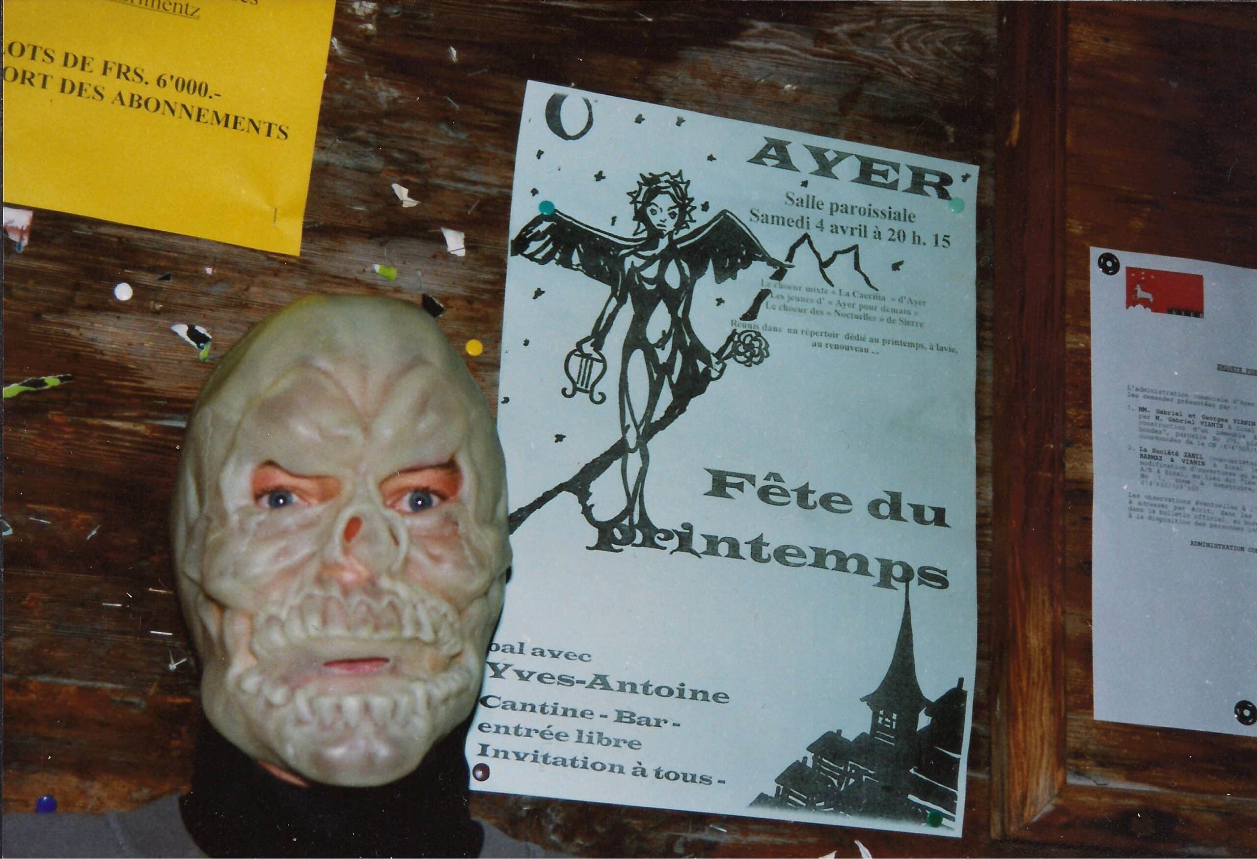 Personne portant un masque de squelette devant un tableau d'affichage.