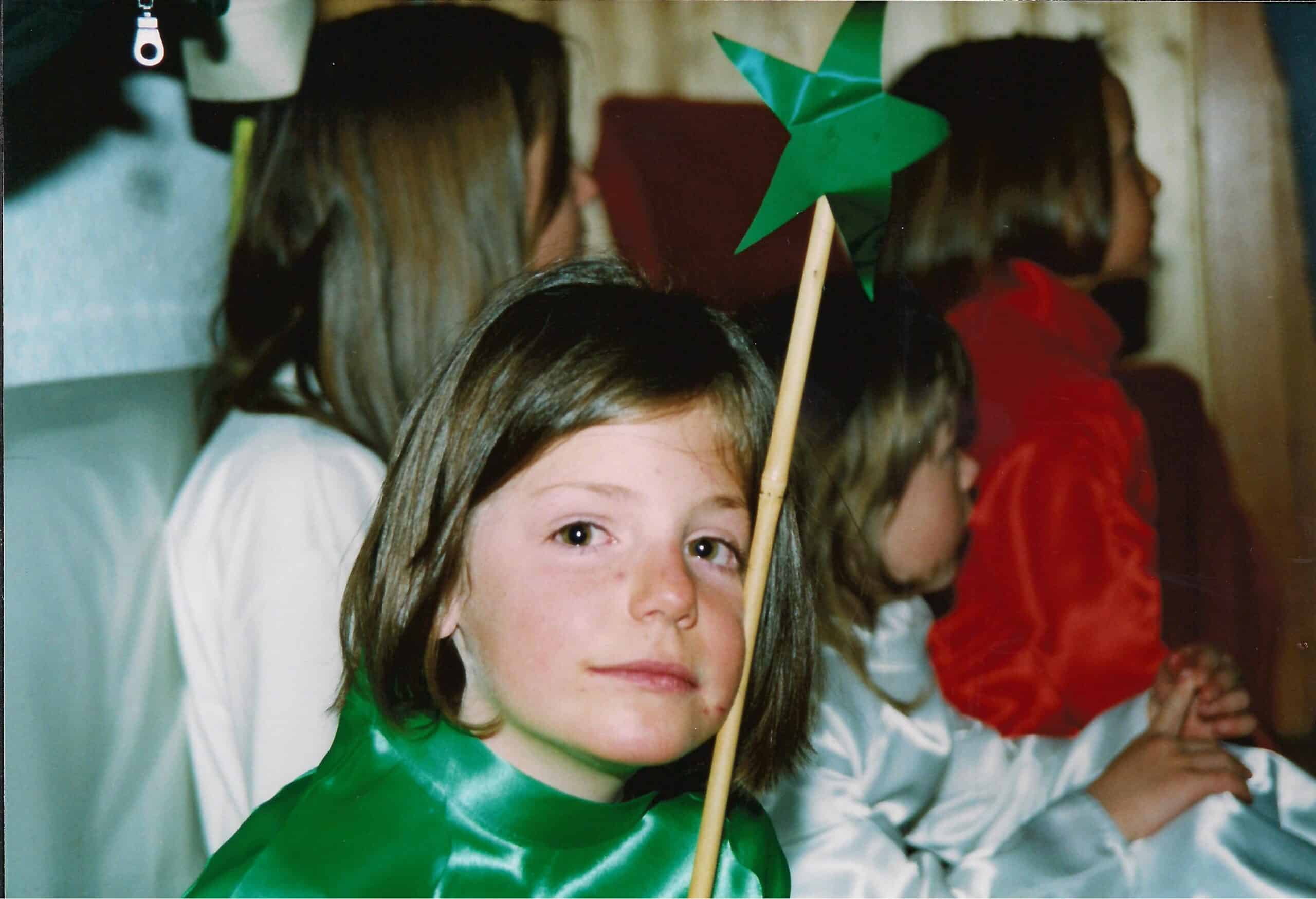 Jeune fille en costume vert tenant une étoile.