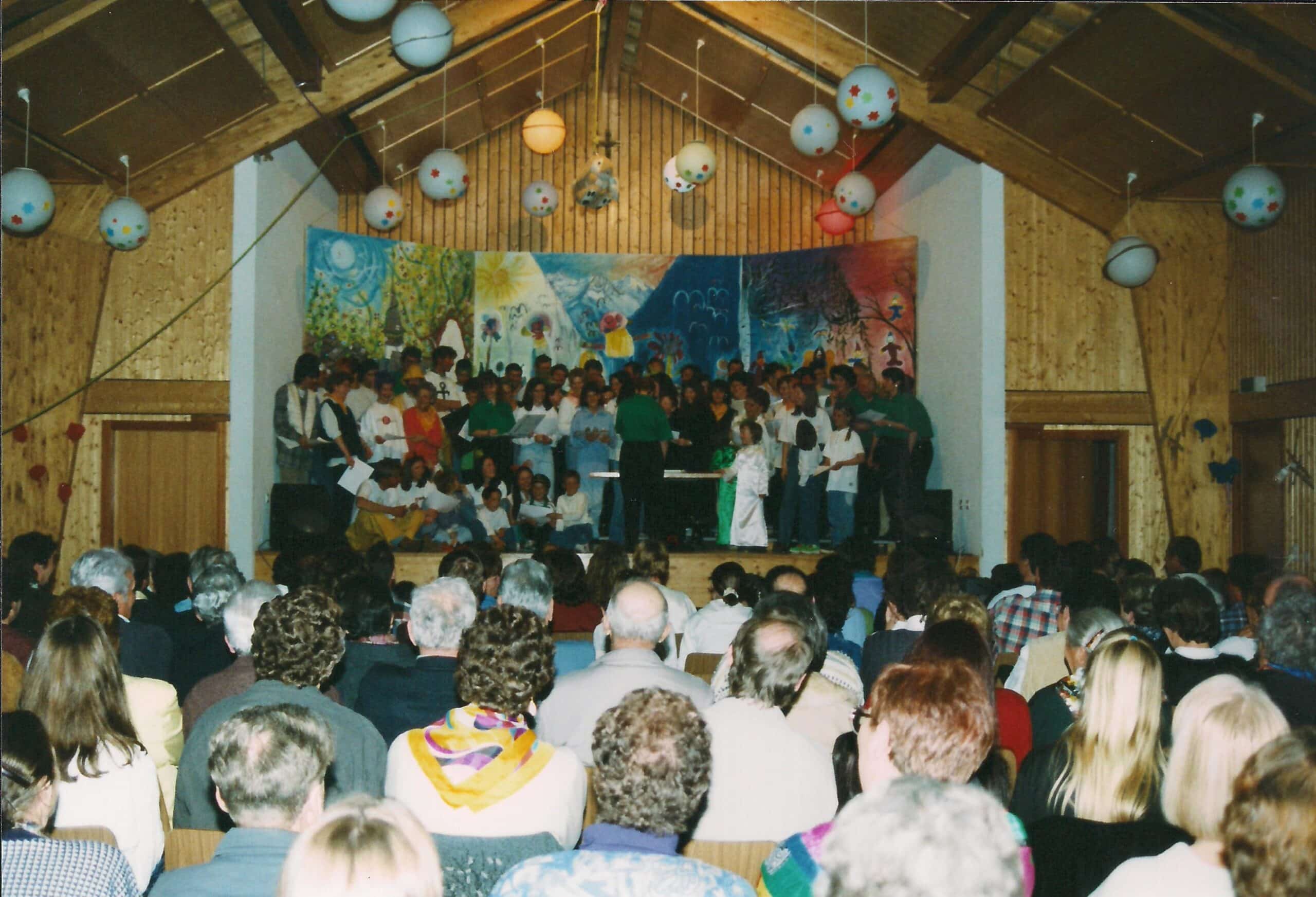 Chorale d'enfants sur scène devant un public dans une salle.