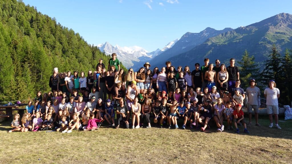 Grand groupe de jeunes posant pour une photo en montagne.