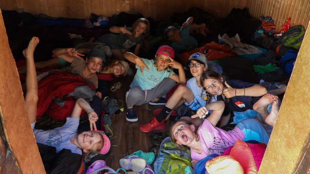 Groupe d'enfants joyeux posant dans un dortoir en bois.