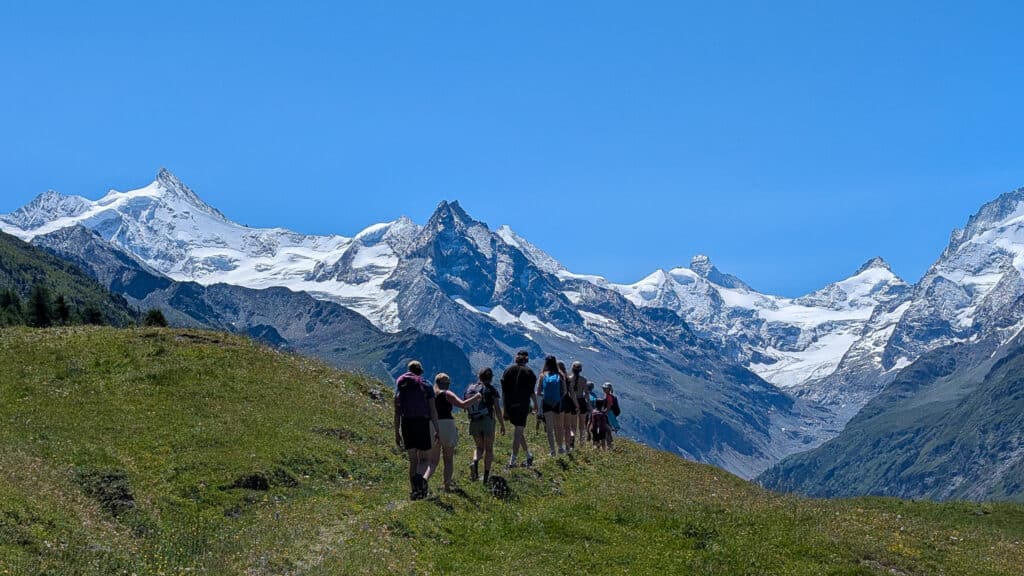 Groupe de randonneurs marchant vers des montagnes enneigées.